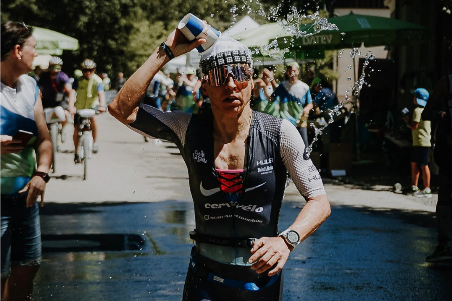 woman pouring water over her head mid race on a swelteringly hot day wearing an omius headband