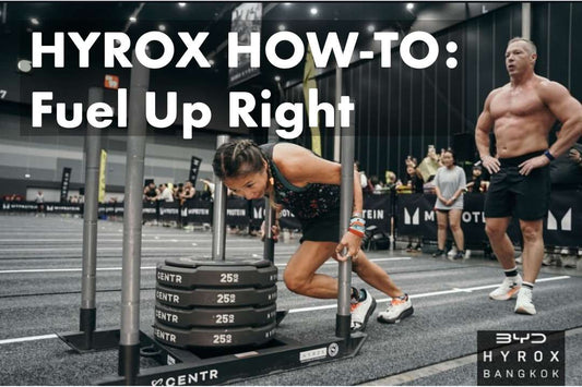 female in pigtails at a Hyrox competition pushing heavy weights while her hyrox partner looks on in preparation for his turn